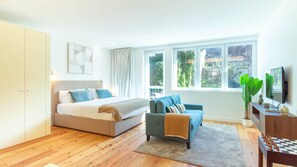 A bedroom with a bed, a sofa, a TV, and a desk with a chessboard. - Central & Trendy w/ Balcony by LovelyStay (Porto)