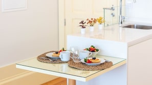 A breakfast setup with pancakes, berries, and coffee on a glass table in a modern kitchen. - Central & Trendy w/ Balcony by LovelyStay (Porto)