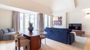 A modern living room with a dining table, sofa, and TV. - Catarina 392 | Premium Duplex by LovelyStay (Porto)