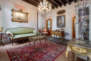 A room with a green sofa, a chandelier, a red patterned rug, and a wooden cabinet. - Historic San Marco Apartment with Authentic Venetian Elegance (Venezia)