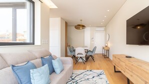 A modern living space with a sofa, dining table, chairs, and a TV. - Coastal 3BR Duplex w/ Terrace by LovelyStay (Matosinhos)