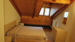 A bedroom with a wooden ceiling, two beds, a dresser, and a window. - Apartment 6 Maso Anna (Mastellina)
