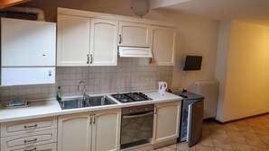 A kitchen with white cabinets, a stove, a sink, and a refrigerator. - Apartment 6 Maso Anna (Mastellina)