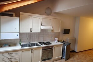 A kitchen with white cabinets, a stove, a sink, and a refrigerator. - Apartment 6 Maso Anna (Mastellina)