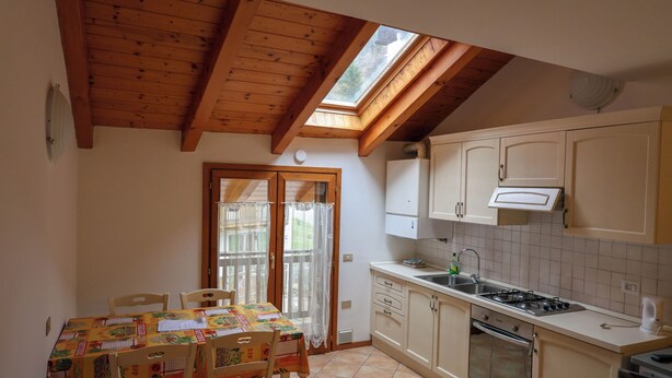 A kitchen with wooden beams, a dining table with chairs, a window, and a sink. - Apartment 6 Maso Anna (Mastellina)