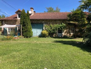 Uma casa de pedra com telhado em tijolos, quintal cercado e antena parabólica.