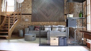 A living room with a sofa, a coffee table, a bookshelf, a lamp, and a staircase. - Atypical gite in Dordogne-Périgord, quiet, with swimming pool and beautiful view (Manzac-sur-Vern)