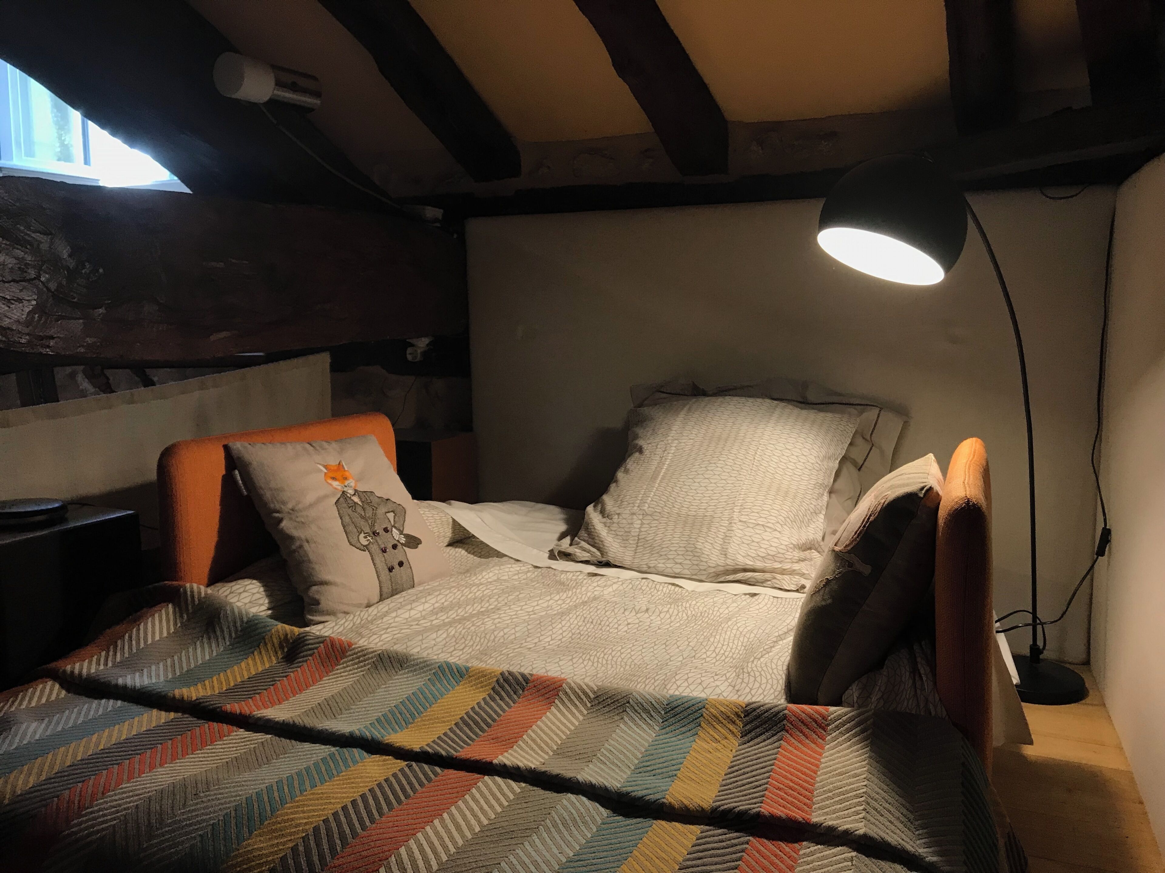 Ein gemütliches Schlafzimmer mit einem Bett, einem Sessel, einer Lampe und einem Fenster.