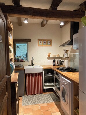 A compact kitchen with a sink, stove, oven, and washing machine. - Atypical gite in Dordogne-Périgord, quiet, with swimming pool and beautiful view (Manzac-sur-Vern)