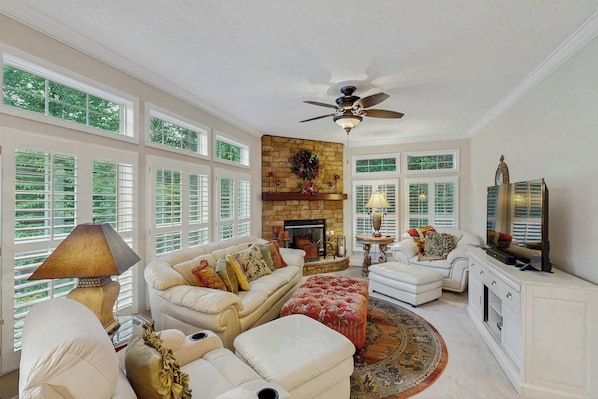 A spacious living room with a fireplace, white furniture, and large windows. - Cozy house w/ mountain views, deck, outdoor dining, dog-friendly, jacuzzi, w/d (Sylva)
