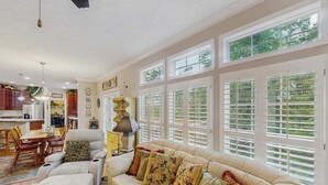 A spacious living room with a large beige sofa, a dining area with wooden chairs, and a kitchen in the background. - Ward Retreat (Sylva)