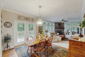 A dining area with a wooden table and chairs, a chandelier, and a fireplace in the background. - Cozy house w/ mountain views, deck, outdoor dining, dog-friendly, jacuzzi, w/d (Sylva)