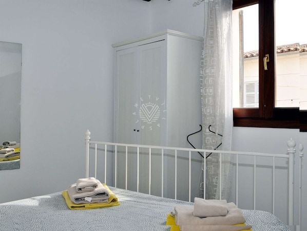 Un dormitorio con cama, armario y ventana con cortinas.