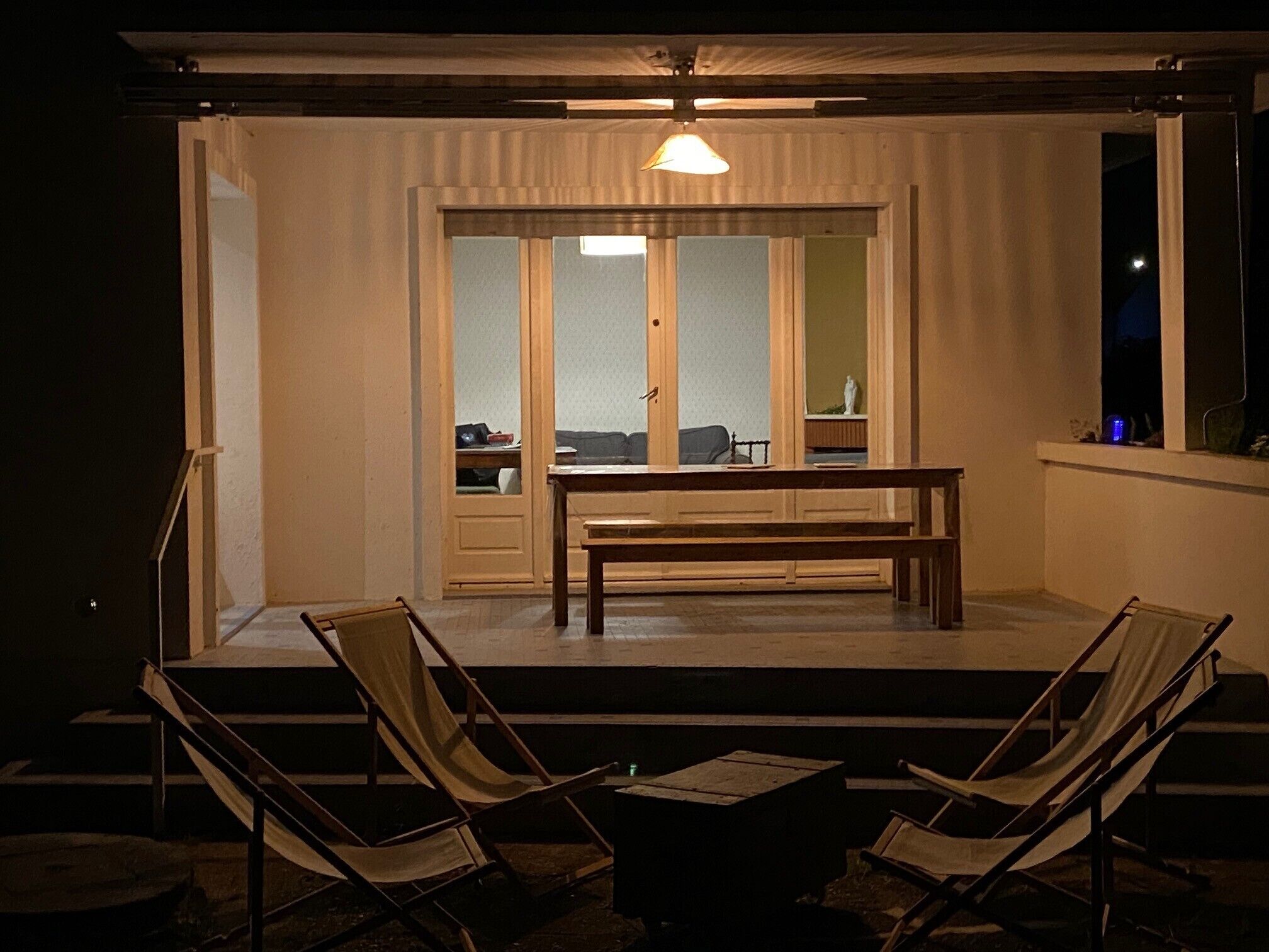 A room with a wooden bench, two chairs, a table, and a large window with a view.