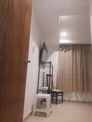 A room with a wooden door, a black metal shelf with a mirror, a small white stool, and a chair. - Diamantes Boutique (Acapulco de Juárez)