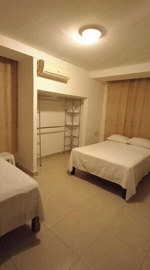 Ein Zimmer mit zwei Betten, einem Kleiderschrank und einer Klimaanlage.