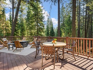 Une terrasse extérieure avec des meubles en bois, une table ronde et un foyer.