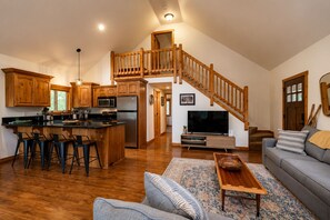 A spacious living area with a wooden staircase, a kitchen with modern appliances, and a cozy seating area.