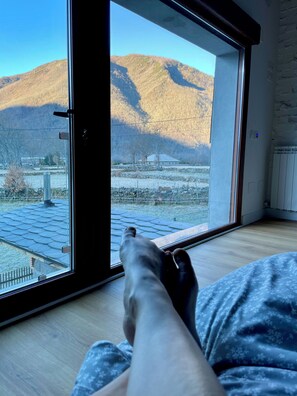 A room with a large window, a wooden floor, and a view of a mountainous landscape. - Quiet design duplex with mountain views (Villablino)