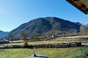 Een bergachtig landschap met heldere lucht, stenen muren en schaarse begroeiing.