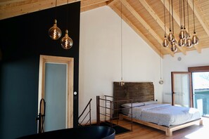 A modern bedroom with a bed, wooden beams, and hanging light fixtures. - Quiet design duplex with mountain views (Villablino)