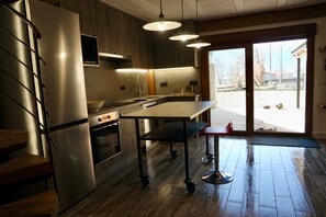 Una cucina moderna con frigorifero, forno e microonde in acciaio inossidabile, un piano di lavoro in legno e un'ampia finestra con vista sull'esterno.