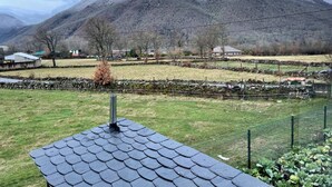 Paesaggio rurale con una montagna, muri in pietra e un'area recintata con vegetazione.