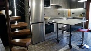 Una cucina moderna con forno integrato, frigorifero in acciaio inossidabile e una scala in legno.