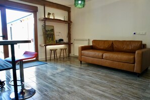 Un soggiorno con un divano in pelle marrone, un tavolino in legno e un quadro appeso al muro.