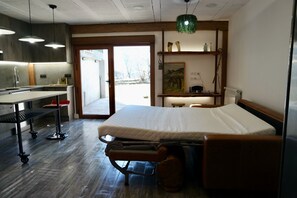 Una stanza con un letto, una scrivania, una sedia, un termosifone e una porta che dà sull'esterno.
