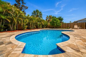A swimming pool with a curved edge, surrounded by a wooden fence and tropical vegetation. - Tropical Largo Pool House Near Beaches | Private Pool Retreat (Largo)