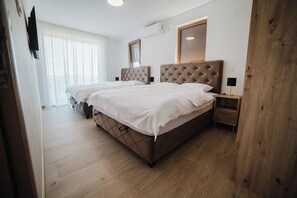 Ett hotellrum med två sängar, ett trägolv, en TV och ett fönster med persienner.