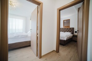 Une chambre à coucher comprenant un lit, une table de chevet, un miroir et une porte donnant sur une autre pièce.