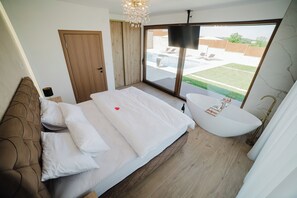 A bedroom with a bed, a large window, a bathtub, and a door leading to a balcony.