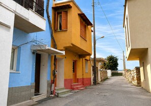 A narrow street with colorful buildings, a stone wall, and a clear sky. - Elegant Studio in Chios Near the Beach and Port (Chios)