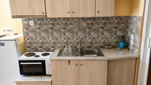 A compact kitchen with a stove, sink, and wooden cabinets. - Elegant Studio in Chios Near the Beach and Port (Chios)