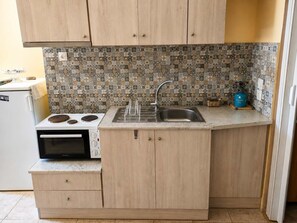 A compact kitchen with a stove, sink, and wooden cabinets. - Elegant Studio in Chios Near the Beach and Port (Chios)