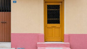 A yellow door with a black metal gate, a pink wall, and a blue house number sign. - Elegant Studio in Chios Near the Beach and Port (Chios)