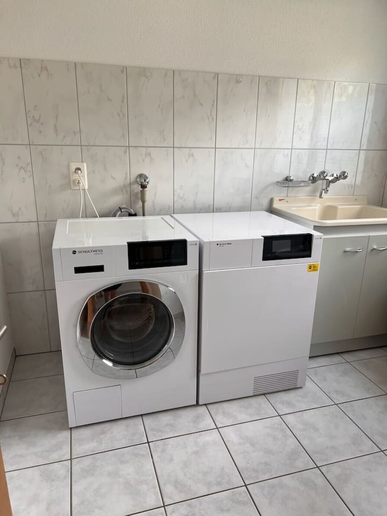 Ein Waschbereich mit einer Waschmaschine mit Frontlader und einem Waschbecken.