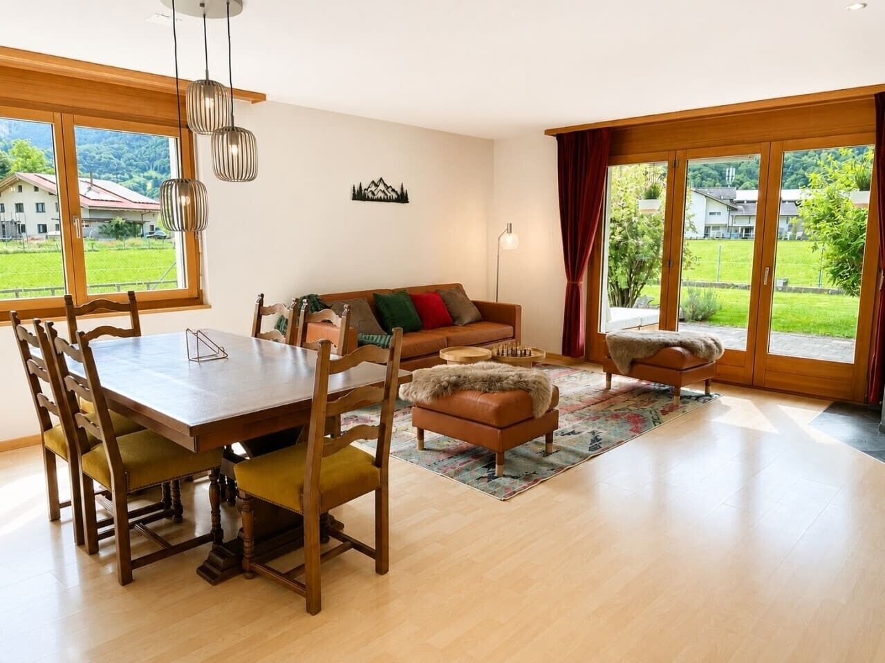 A spacious living area with a wooden dining table, chairs, a sofa, and a coffee table.