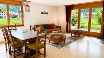 A spacious living area with a wooden dining table, chairs, a sofa, and a coffee table.
