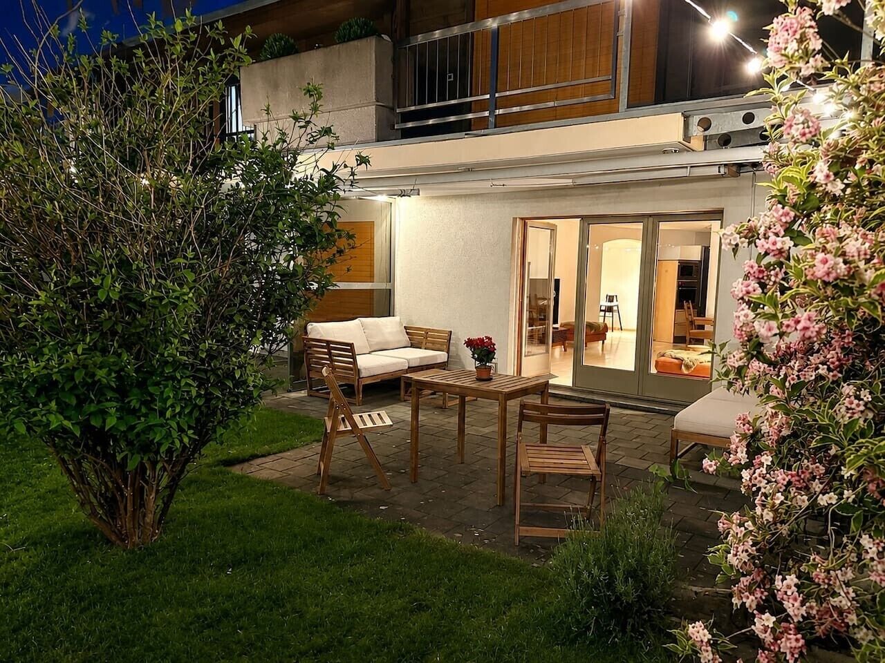 Eine Terrasse mit Gartenmöbeln, einem kleinen Tisch und einem Blumentopf.