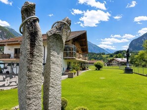 A mountain lodge with a wooden exterior, a well-maintained lawn, and a clear view of the surrounding mountains. - Waterfall 3BR Garden Apt near Interlaken • AC by SwissDreamLiving (Meiringen)