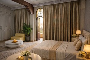A bedroom with a large bed, a sofa, a round coffee table, and a potted plant. - "Elegant Fully Equipped Apartment with Garden View. (Taroudant)
