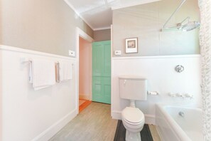 A bathroom with a toilet, bathtub, and a green door. - Upscale Historic West End Townhouse with Expansive Garden (Portland)