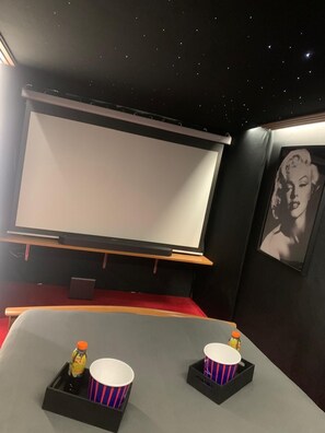 Un cine con una pantalla grande, asientos rojos y un cuadro en la pared.