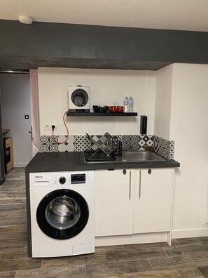Een praktische keuken met een wasmachine, een klein aanrecht en een magnetron.