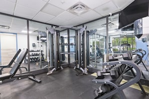 Ett gym med utrustning för styrketräning, träningsbänkar och hantlar.