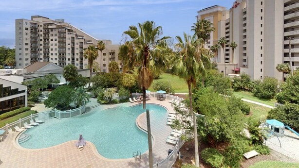 Un resort con piscina, palmeras y edificios de gran altura.