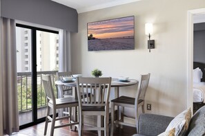 A dining area with a table and chairs, a view of the sea through a window, and a wall-mounted light fixture. - Orlando Family Resort - 2 Miles to Universal! (Orlando)